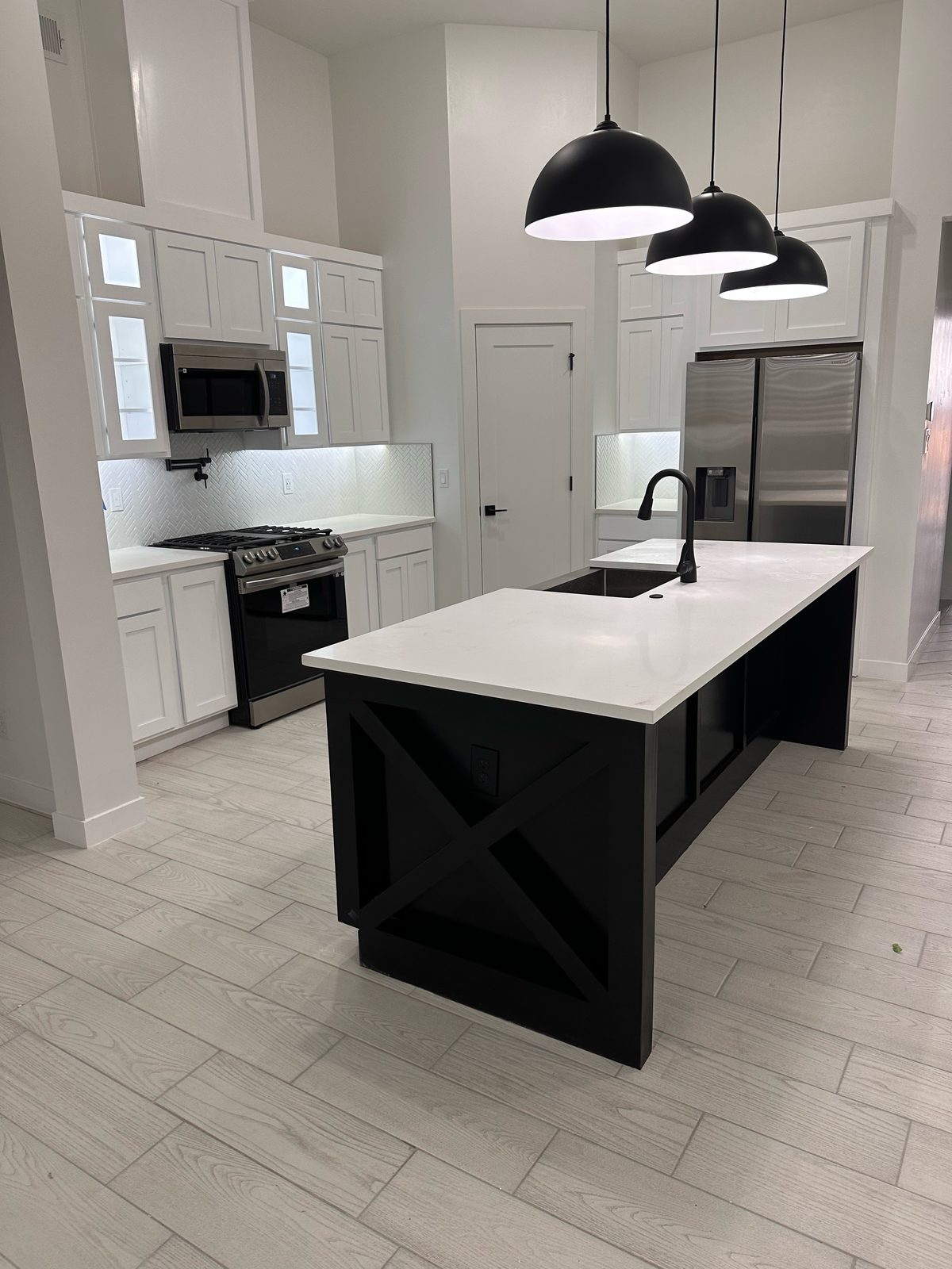 White shaker kitchen with black island, quartz top and black pendant lights